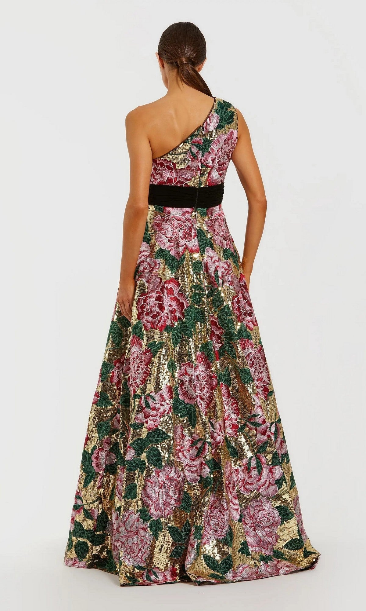 A woman faces away, wearing the Mac Duggal 21194 long formal dress—a floor-length, one-shoulder sequin ballgown with a black waist band and pink, green, and gold floral embroidery.